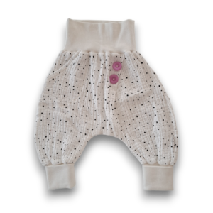 Locker geschnittene Babyhose aus weißem Stoff mit schwarzen Punkten und zwei lila Knöpfen am Bund.