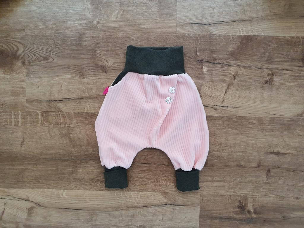 Babyhose in Rosa mit dunklen Bündchen auf Holzfussboden