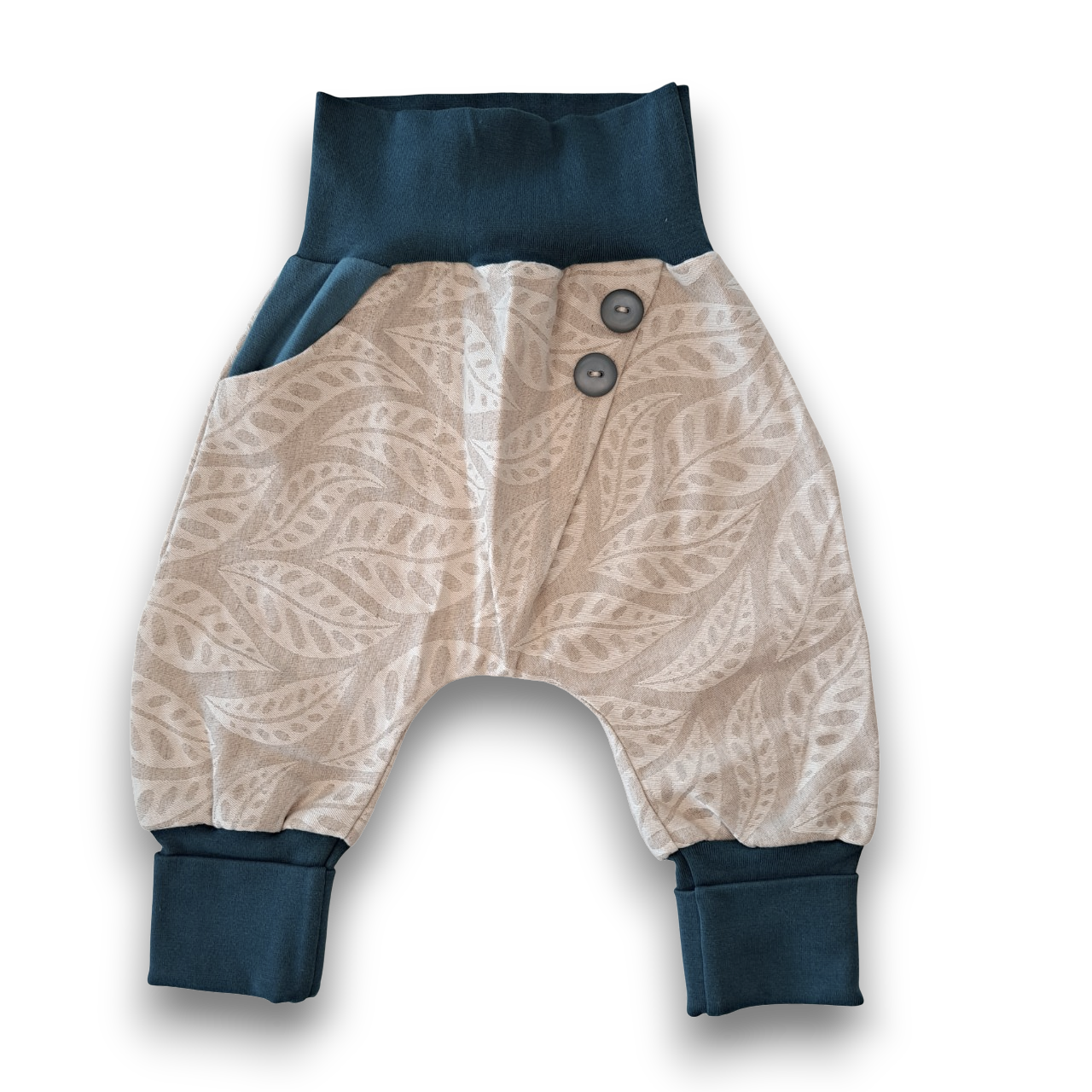 Baby-Haremshose aus beigefarbenem Stoff mit hellem Blättermuster, dunkelblauen Bündchen und zwei dunkelblauen Knöpfen am Bund.