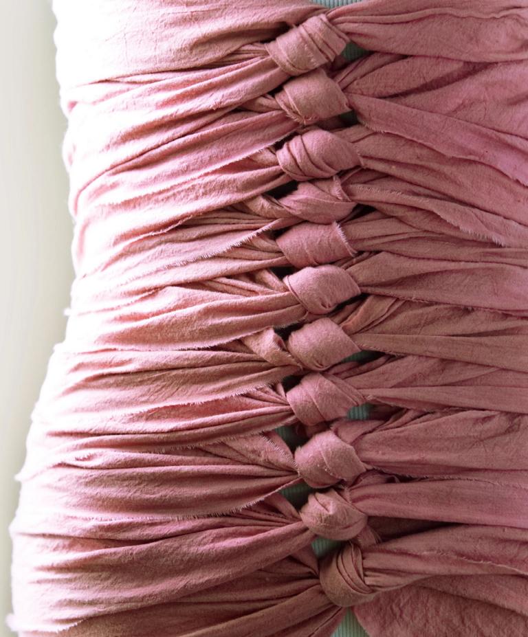 Nahaufnahme eines Bengkung Belly Bind aus Baumwolle mit traditioneller Knotentechnik an einer Schneiderpuppe, Farbe Alt-Rosa